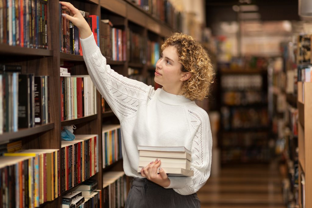 Jovem escolhendo livros em uma livraria, segurando exemplares e explorando as prateleiras repletas de opções literárias.
