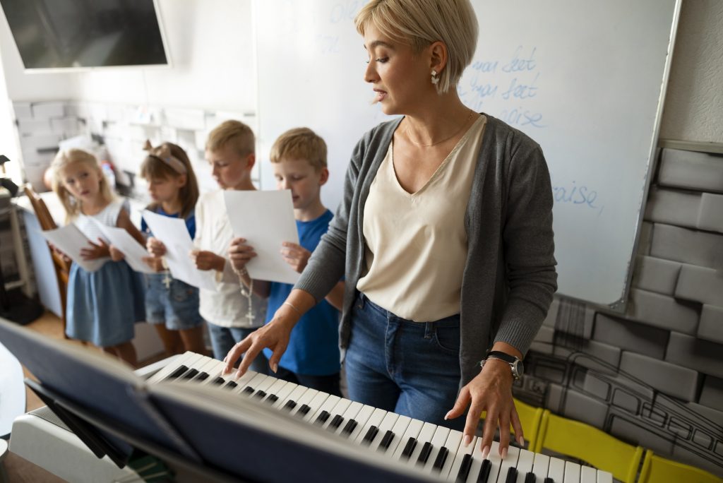 Professora tocando piano enquanto orienta crianças em uma aula de música.
