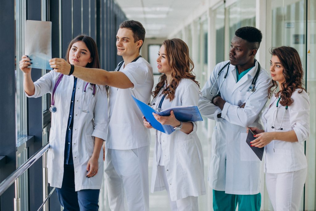 Grupo de jovens enfermeiros analisando uma radiografia em um corredor de hospital.