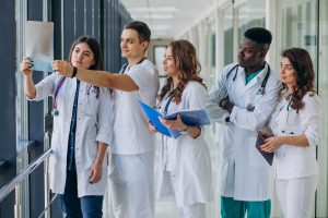 Grupo de jovens enfermeiros analisando uma radiografia em um corredor de hospital.