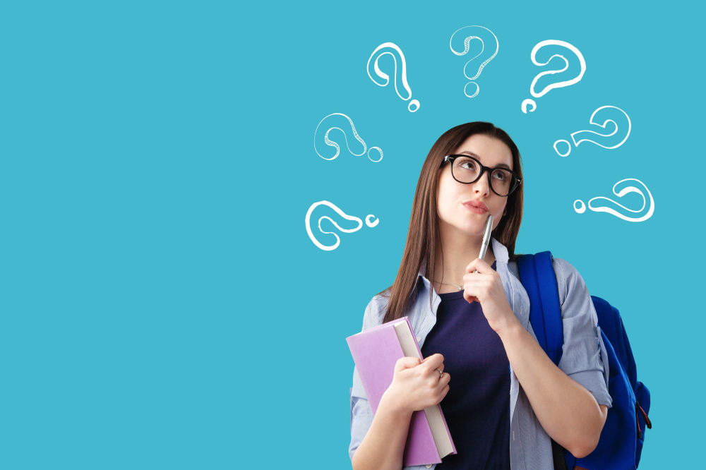 Estudante pensativa com óculos, segurando um livro e uma caneta, com pontos de interrogação desenhados ao fundo, simbolizando indecisão ou dúvida.