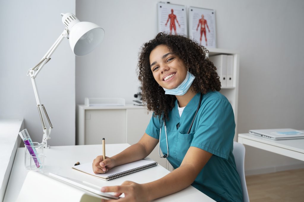 Estudante de medicina com jaleco e estetoscópio sorrindo enquanto estuda – imagem ilustrativa sobre burnout entre estudantes de medicina.